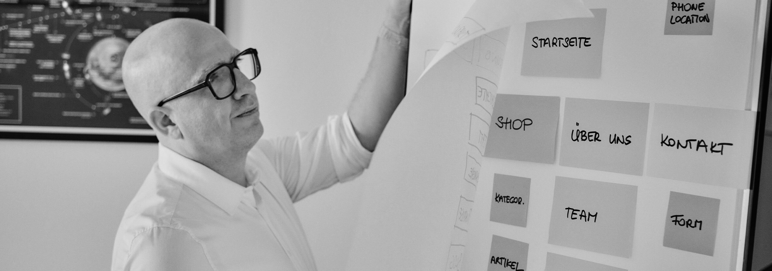 Horst Köpfelsberger vor der Flipchart, reißt ein Blatt mit Post-Its ab.